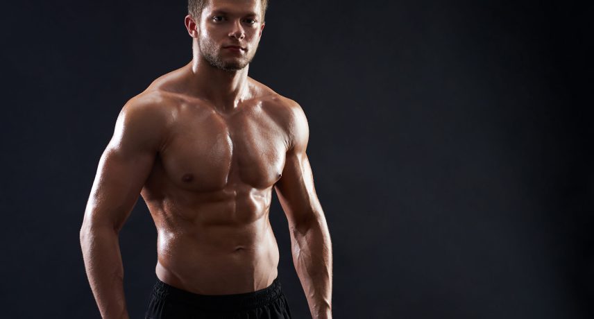 Young muscular fit sportsman posing shirtless on black backgroun